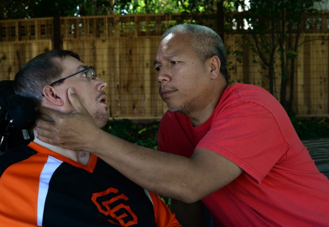 Caregiver Bentley Wan with Brad Dreyer, 26, who suffered a severe brain injury five years ago. Wan spends many moments of the day trying to reach Dreyer through touching, talking and lots of eye contact. (Photos by Erik Castro)
