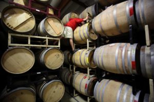 Hardy Wallace with Dirty and Rowdy Family Wines climbs up the tall stacks of barrels at Punchdown Cellars to pull a sample in Santa Rosa on Tuesday, July  15, 2014. (Conner Jay/The Press Democrat)