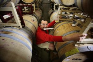 Hardy Wallace with Dirty and Rowdy Family Wines climbs up the tall stacks of barrels at Punchdown Cellars to pull a sample in Santa Rosa on Tuesday, July 15, 2014. (Conner Jay/The Press Democrat) 