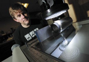 Kevin Ostrom uses a magnifier to inspect a stainless steel bottle for flaws.