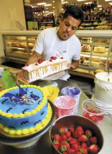 Ruben Altamirano decorates a tres leches cake at Lola's Market in Santa Rosa.