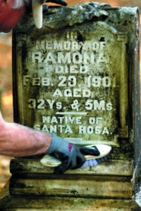 John Dennison, left, and Henry Katz wash away the algae and dirt after Katz finished scrubbing the headstones of the Carrillo family at the Santa Rosa Rural Cemetery. (Photos by John Beck)