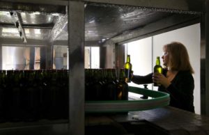 Rachelle Sindle performs quality control as bottles exit a pasteurizing machine on the bottling line at Sonoma Cider, in Healdsburg, on Tuesday, March 1, 2016.   (Christopher Chung/ The Press Democrat)