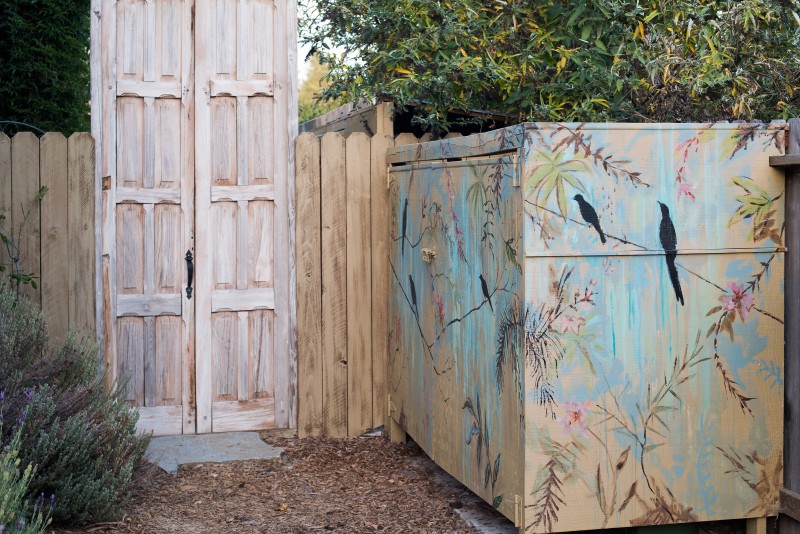 he birds and lowers that decorate a storage shed are painted in subtle colors that blend with nature.