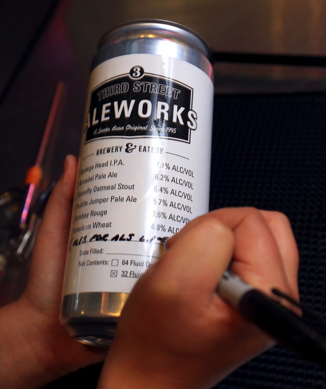 Third Street Aleworks bartender Jordan Thome writes the name of the beer before filling a quart can "Crowler" of their Ales for ALS IPA in Santa Rosa. (JOHN BURGESS 