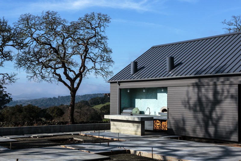 The central courtyard is formed by the L-shaped main home and a new garage and outdoor kitchen. The homes soft gray-brown exterior walls echo the tones of the stone retaining walls and surrounding valley oaks. Muscatine grows Meyer lemons whci she likes to preserve in salt for coooking Morrocan style tagines