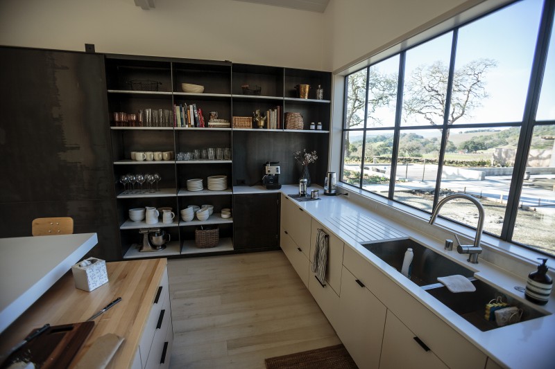 Thoughtful choices in the kitchen keep the overall look clean and simple. The counter has an integrated drain board next to the sink, upright slotted spaces hold baking pans and trays and dishes go straight from the dishwasher onto easyaccess open shelves. Muscatine loves the broad windows and contrast between the cabinetry and blackened steel pantry. 