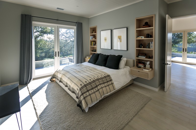 A sense of calm extends into the master bedroom with a soft color palette and cozy gable rug. Muscatine and Madhavan often have their morning coffee here, looking out the floor-to-ceiling windows.