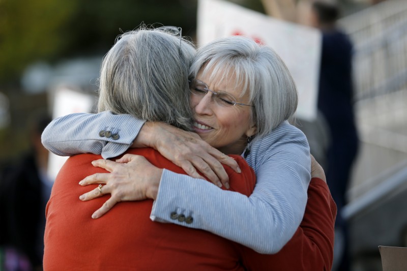 Principal Jeanne Acuña, right, hugs school librarian Gail Bland as community members show their support. (Beth Schlanker)