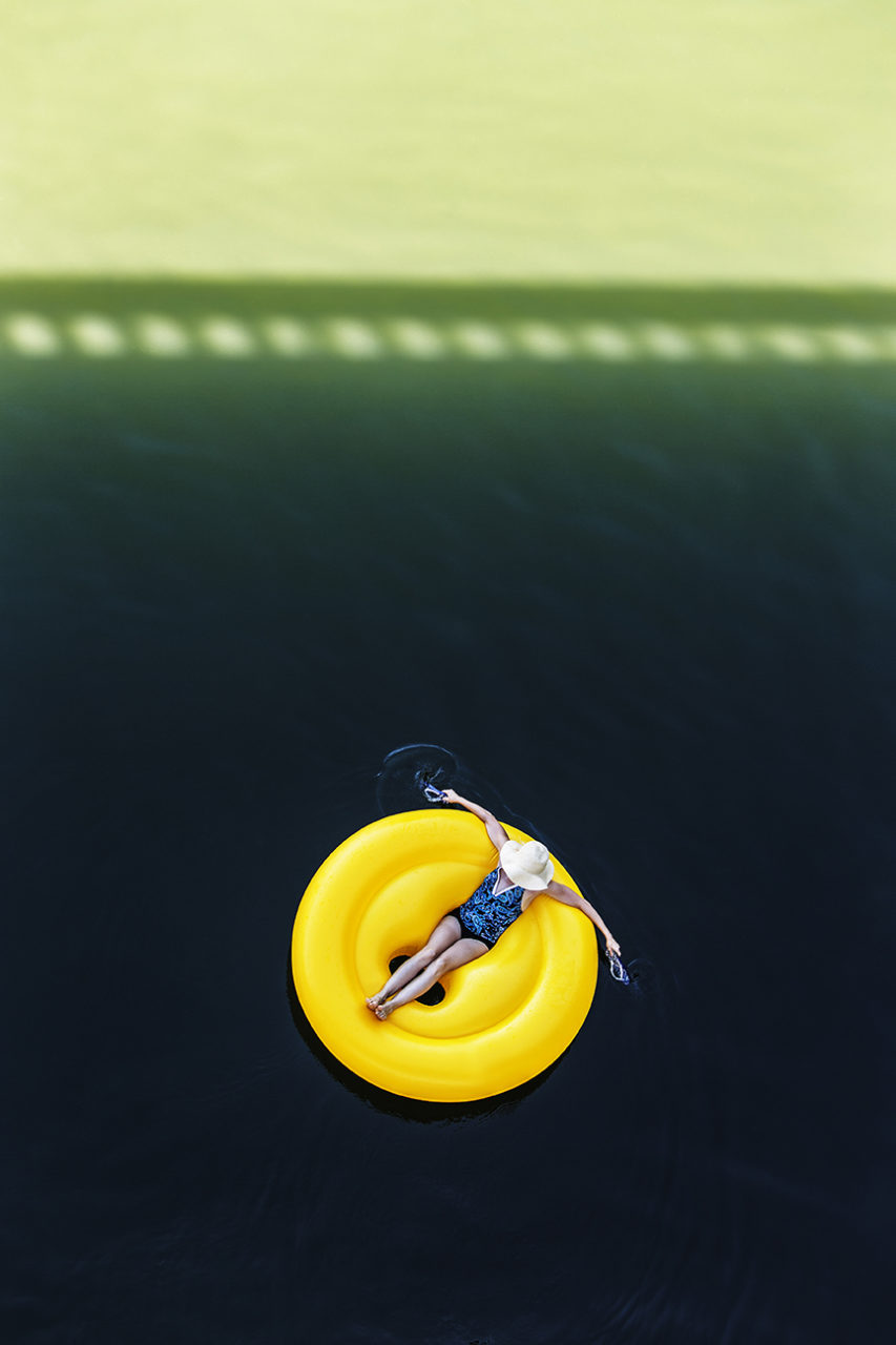 Looking down on a woman floating on a inflatable circular raft on the Russian River in Monte Rio, California.