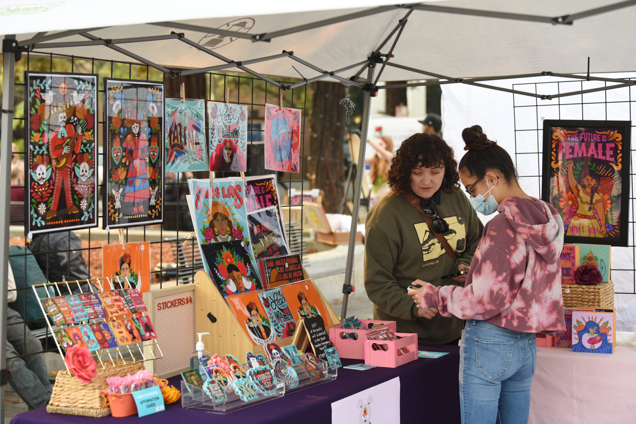 Blanca Molina, left, helps Anisya Lustig make a purchase with her phone at her Pokidi Lab by Blanca Creative booth during The SoCo Market held at Old Courthouse Square in downtown Santa Rosa on Friday, Aug. 20, 2021. (Erik Castro/for The Press Democrat)