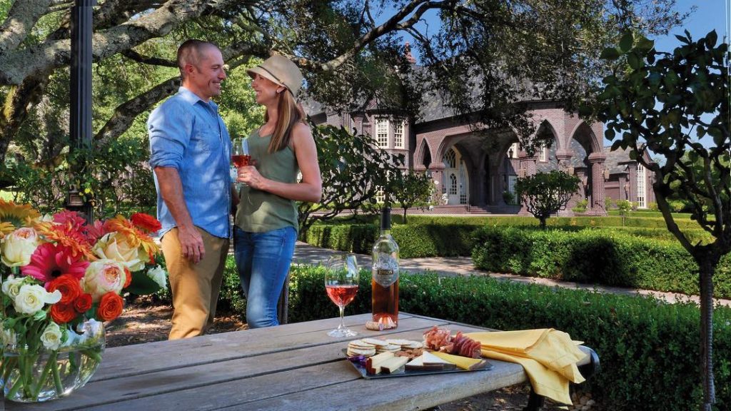 Couple with wine glasses standing by a picnic table at Ledson Winery