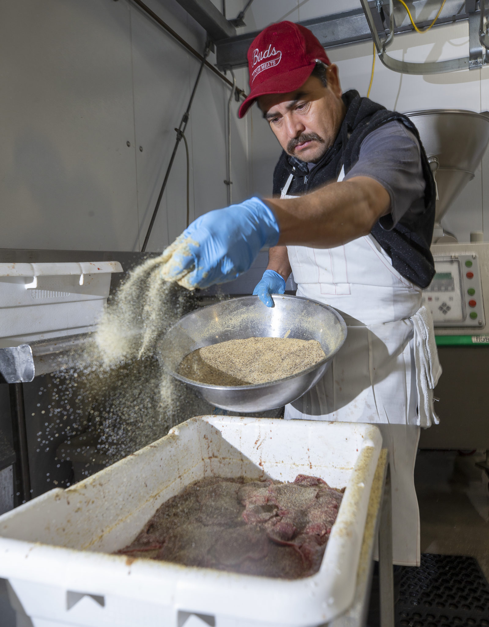 Pedro Arango sprinkles seasoning on the Santa Maria beef jerky at Bud's Meats in Rohnert Park. (photo by John Burgess/The Press Democrat)