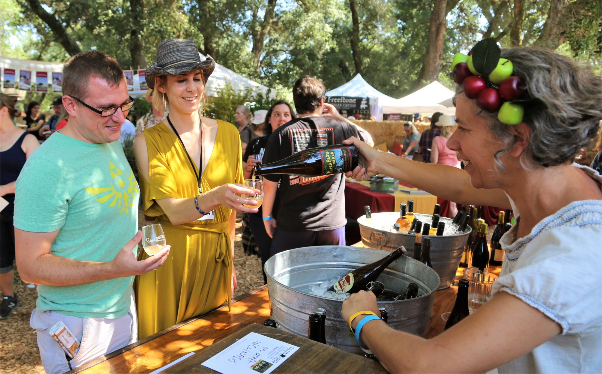 Ellen Cavalli ( right) serves apple cider to Joshua Crawford (left), Livermore and Dana Cappelloni from Healdsburg Sunday August 12th, at the 45th Gravenstein Apple Fair at Ragle Ranch Park in Sebastopol, California. (Will Bucquoy/For The Press Democrat)