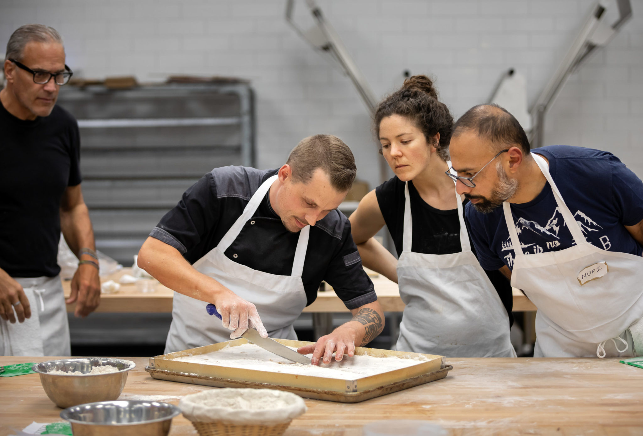 Students Louis Brouillet, left, and Celia Schwenter and Nirupam Singh, at right, watch intensely as chef Pablo Puluke Giet checks his ciabatta dough. (Chris Hardy/For Sonoma Magazine)