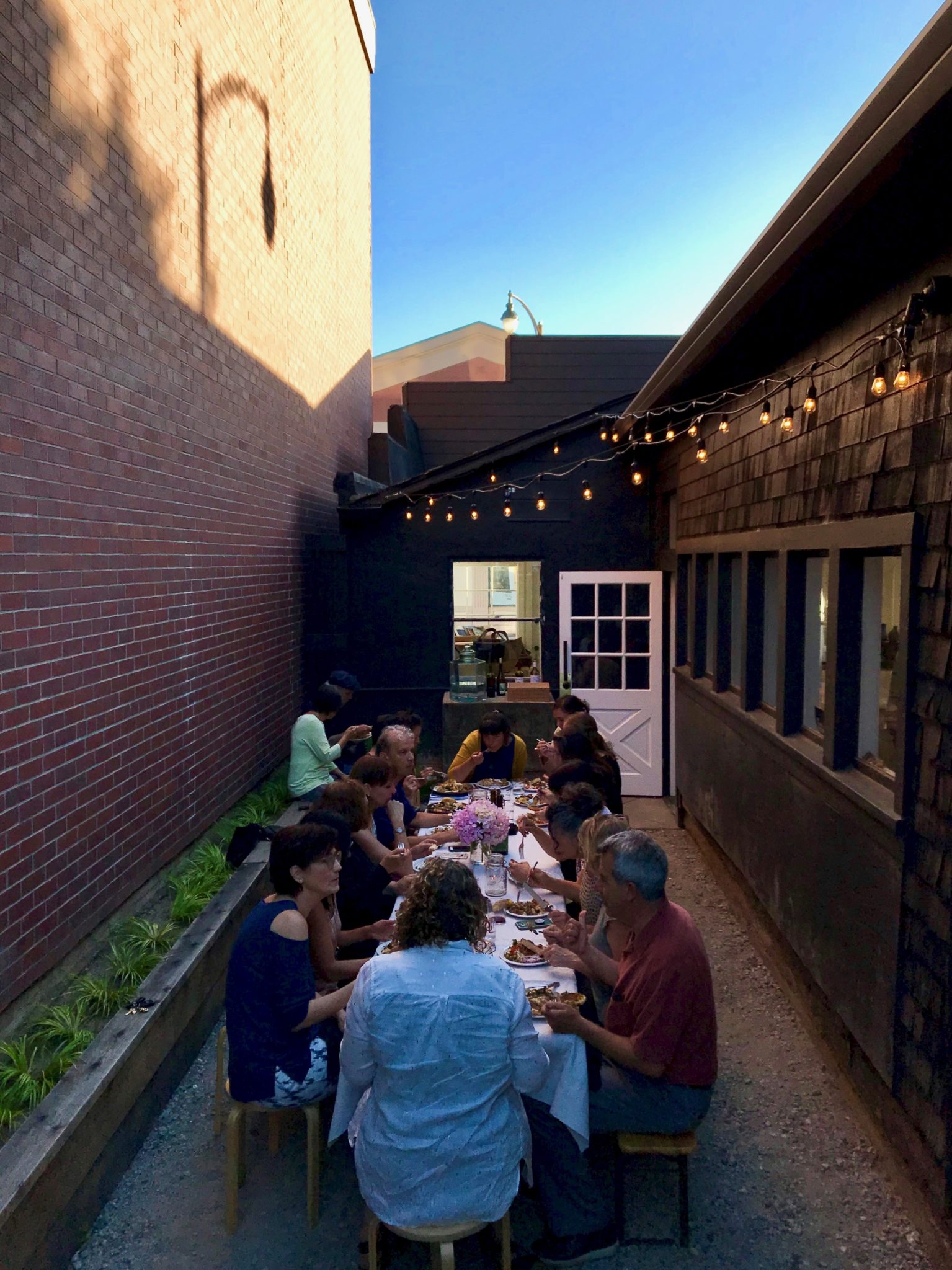 The Miracle Plum Cookbook Club enjoys a potluck dinner in June with dishes from Palestinian author Yasmin Khan's "Zaitoun" cookbook in the courtyard behind Miracle Plum. (Gwen Gunheim)