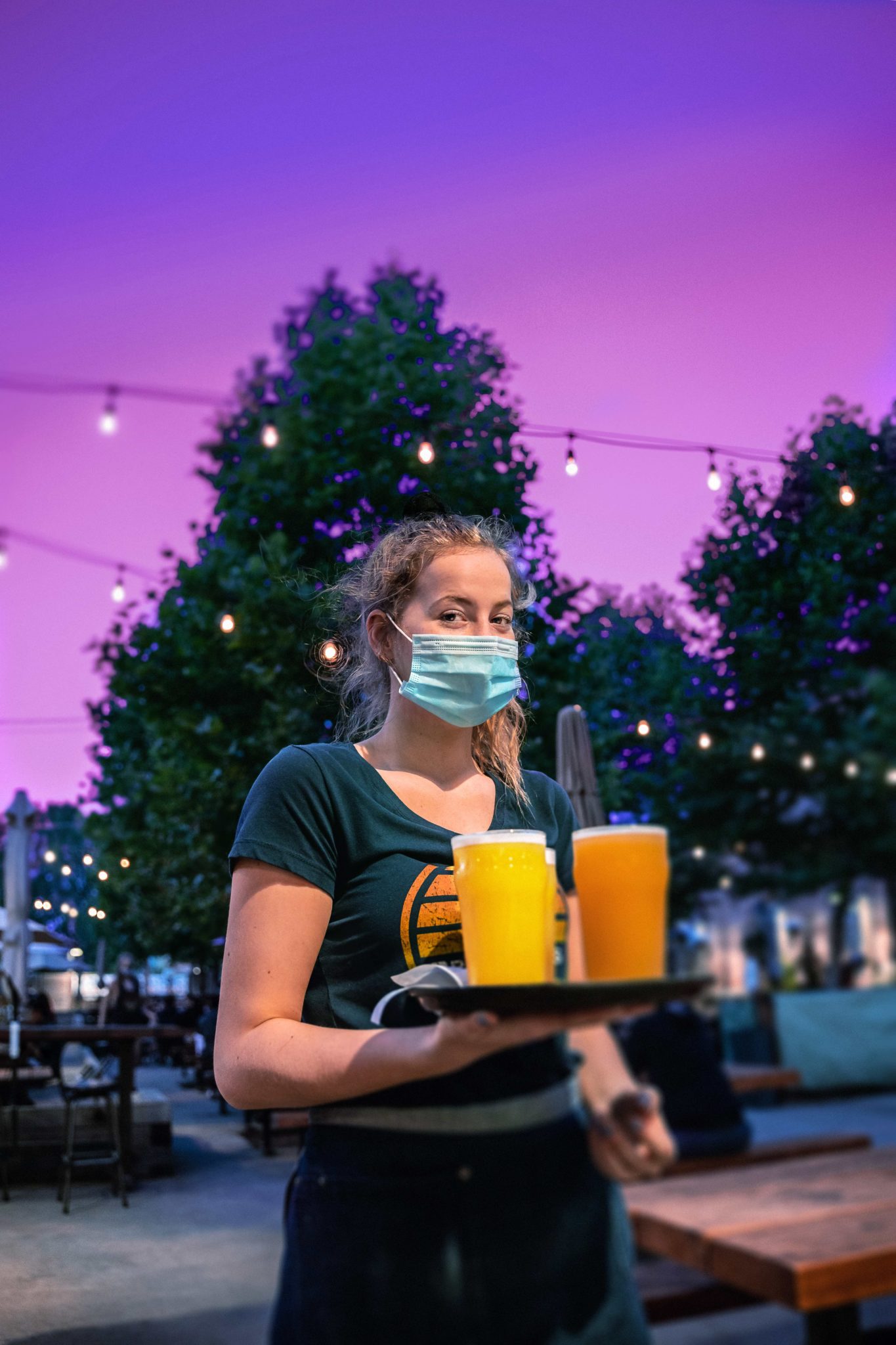 People at Brewsters restaurant using social distancing and face masks Server Olivia Gergus with a tray of beers