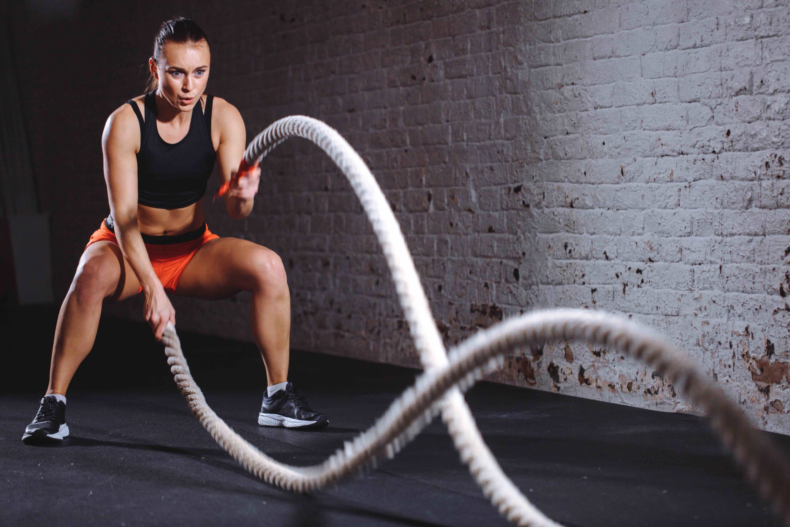 Woman training with battle rope in cross fit gym