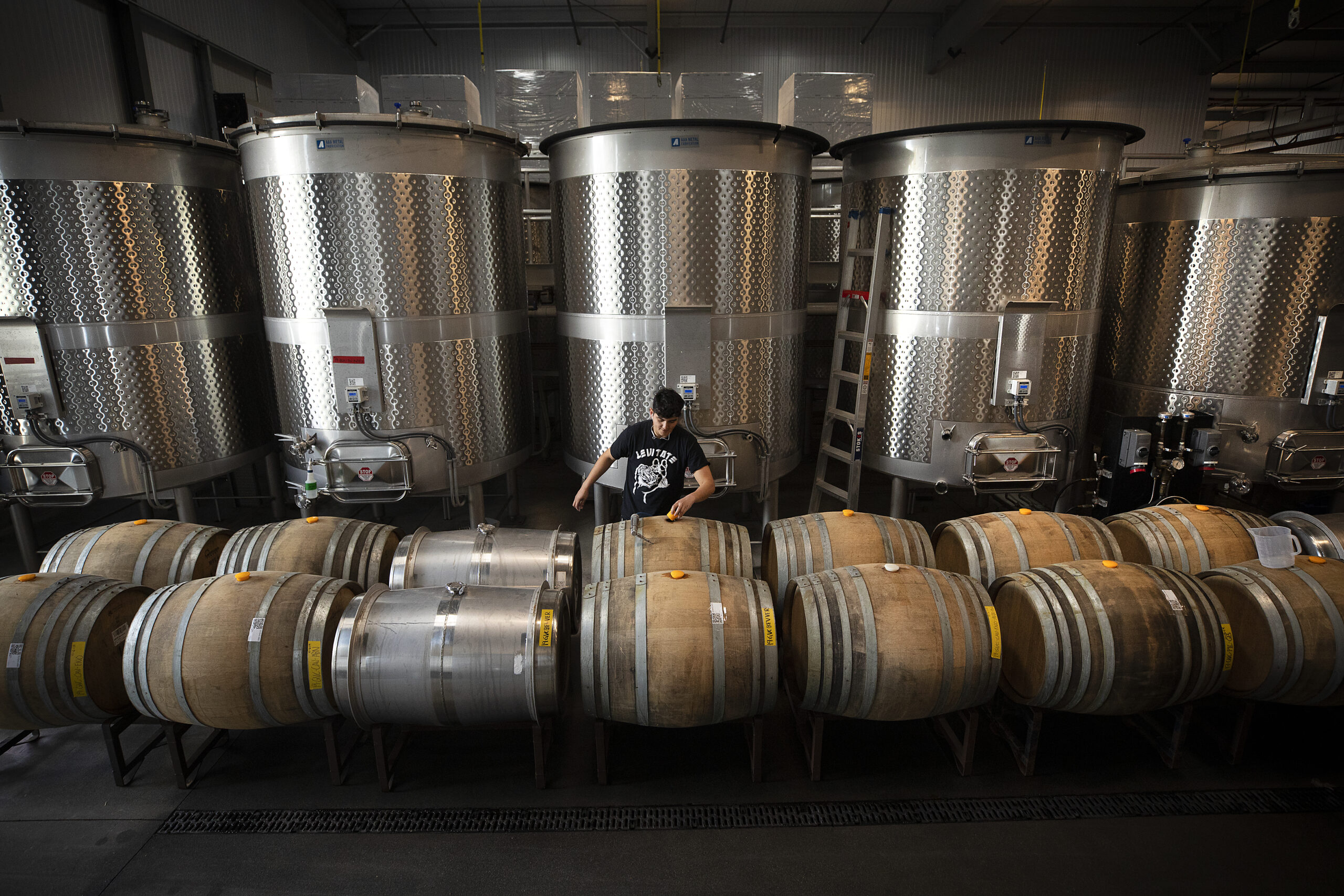 Cristian Ortiz adds sulphur dioxide to wine barrels at the Grand Cru Custom Crush facility in Windsor. (photo by John Burgess/Sonoma Magazine)