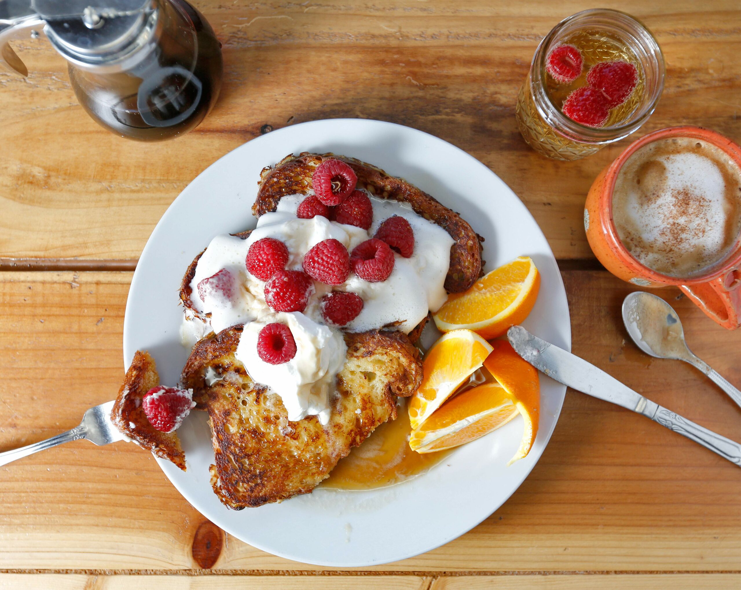 Cinnamon French toast made from Village Bakery brioche topped with butter, fresh whipped cream, organic raspberries and real maple syrup with orange slices, sparkling wine and a cappuccino at Estero Cafe in Valley Ford. (Alvin Jornada/The Press Democrat)