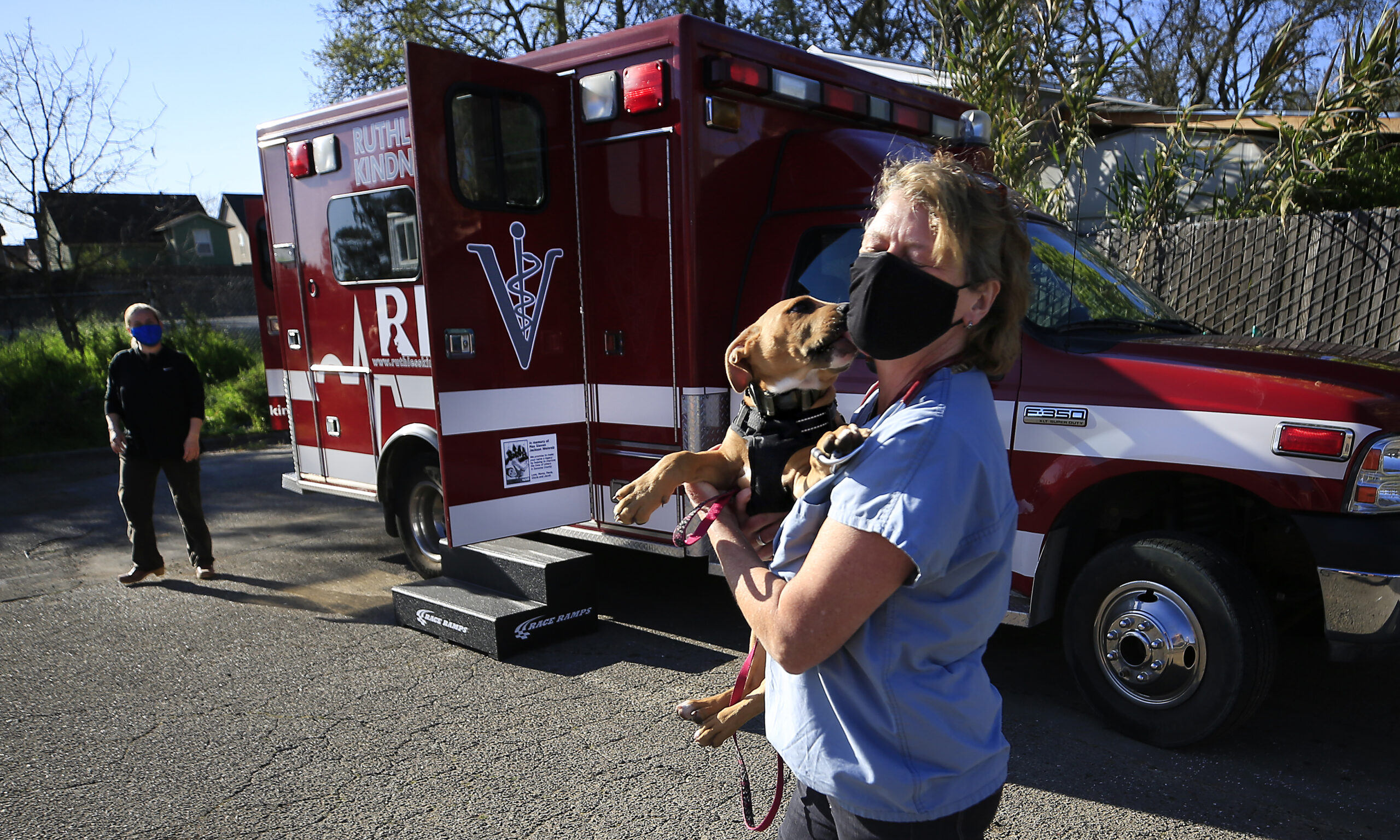 Dr. Kate Kuzminski gets a kisses from Bane, as she and Dr. Sara Reidenbach, left, prepare to examine the puppy in their "Clifford the Big Red Bus," a converted ambulance used as a mobile veterinarian service, Saturday, March 27, 2021, in Santa Rosa. Along with Reidenbach, Kuzminski is a co-founder of the nonprofit Ruthless Kindness, which cares for animals of those owners experiencing homelessness and/or victims of domestic abuse. (Kent Porter / The Press Democrat)