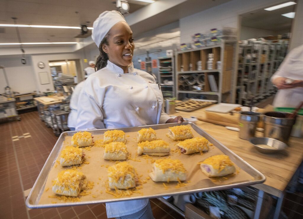 Jessica Crumpton heads to the oven with ham and cheese pastries in the baking class at the SRJC Culinary Arts Center. (John Burgess/The Press Democrat)