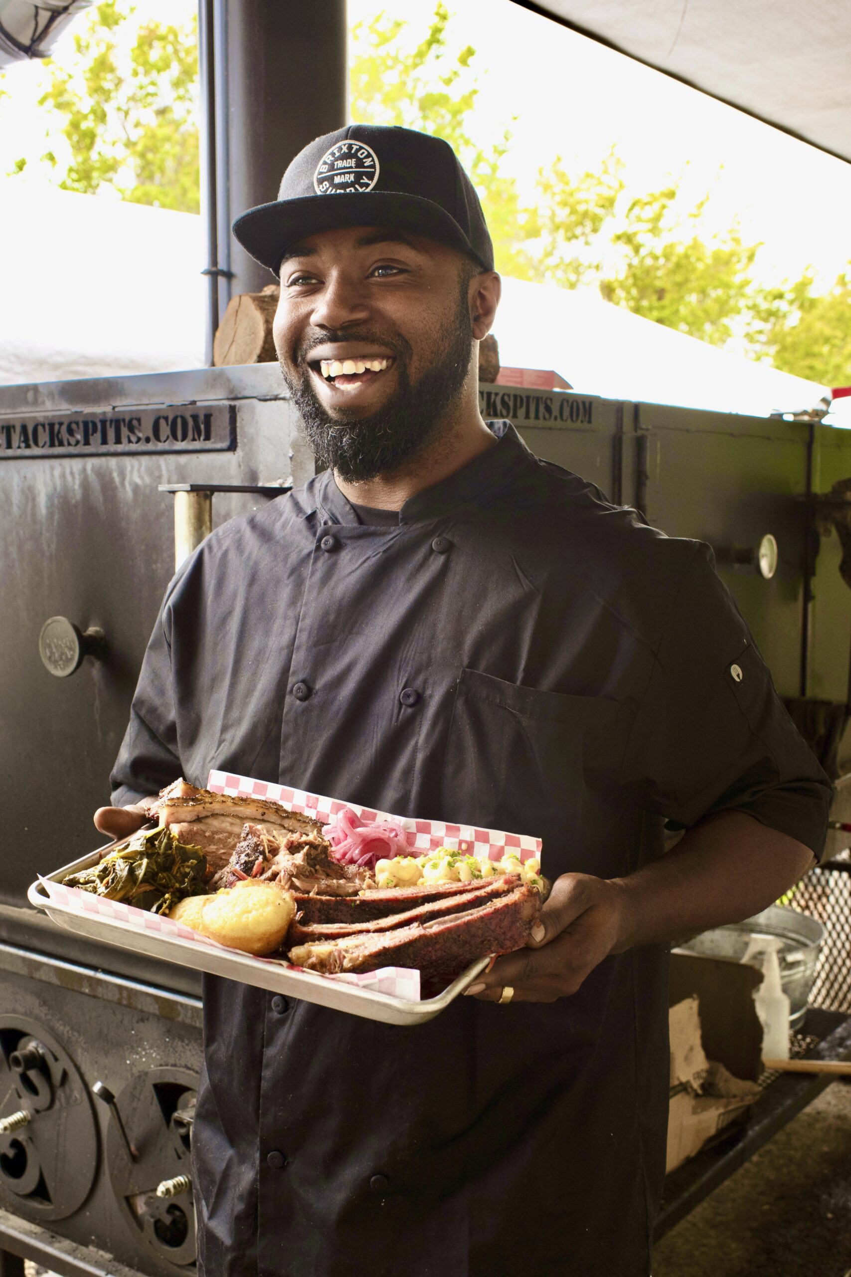 Kris Austin of Austin's Southern Smoke BBQ standing next to his smoker with a tray of his barbecue and all the fixing which he served at Old Possum Brewing Co. in Santa Rosa, California on May 6, 2022. (Photo: Erik Castro/for Sonoma Magazine)