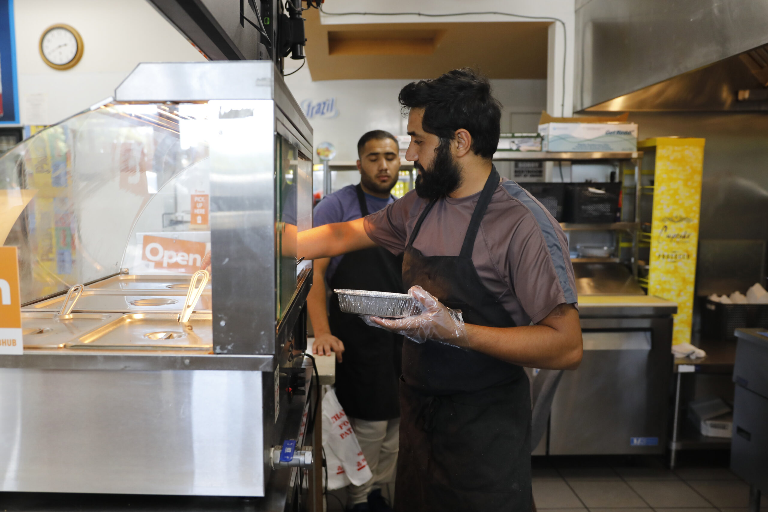 Roman Zemari and his brother Suliman Dawood, rear, cook at ZamZam in Santa Rosa, Calif. on Monday, July 25, 2022. (Beth Schlanker/The Press Democrat)