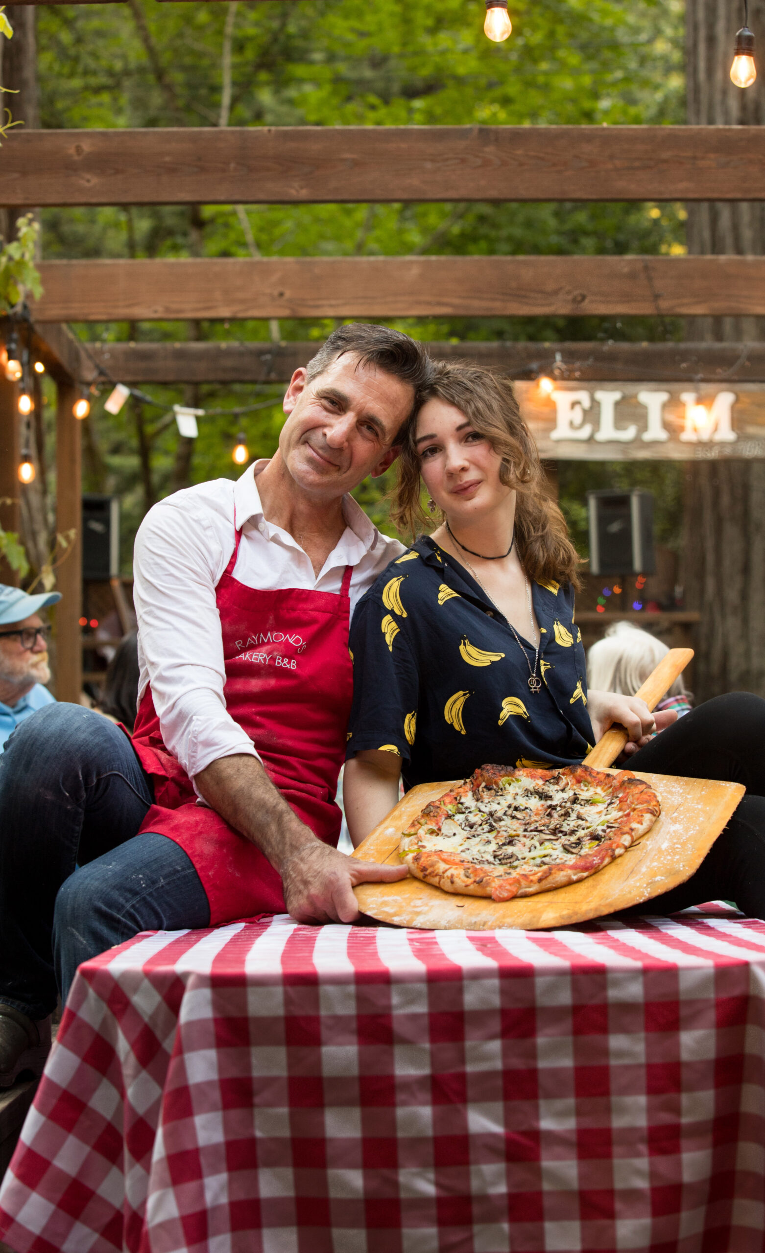 Owner, Mark Weiss, and his daughter who works at the bakery, Ella Weiss, 17, hold one of their pizzas, during community pizza night with live music at Raymond's Bakery, in Cazadero, Calif., on Friday, May 13, 2022. (Photo by Darryl Bush / For The Press Democrat)