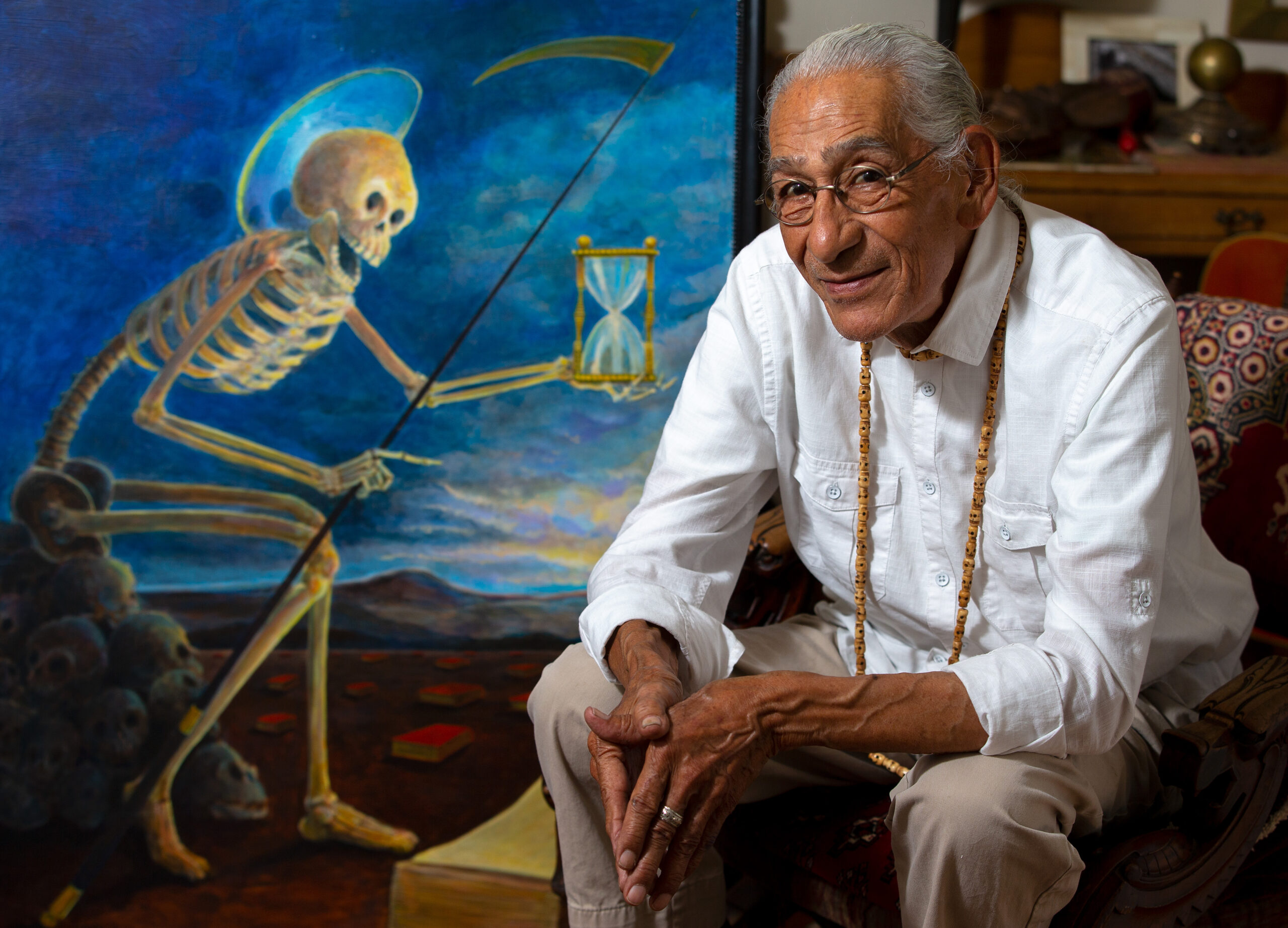 Artist Peter Perez sits beside a painting he created of the Saint of Death, at his home in Santa Rosa, California, on Thursday, October 22, 2020. (Alvin A.H. Jornada / The Press Democrat)