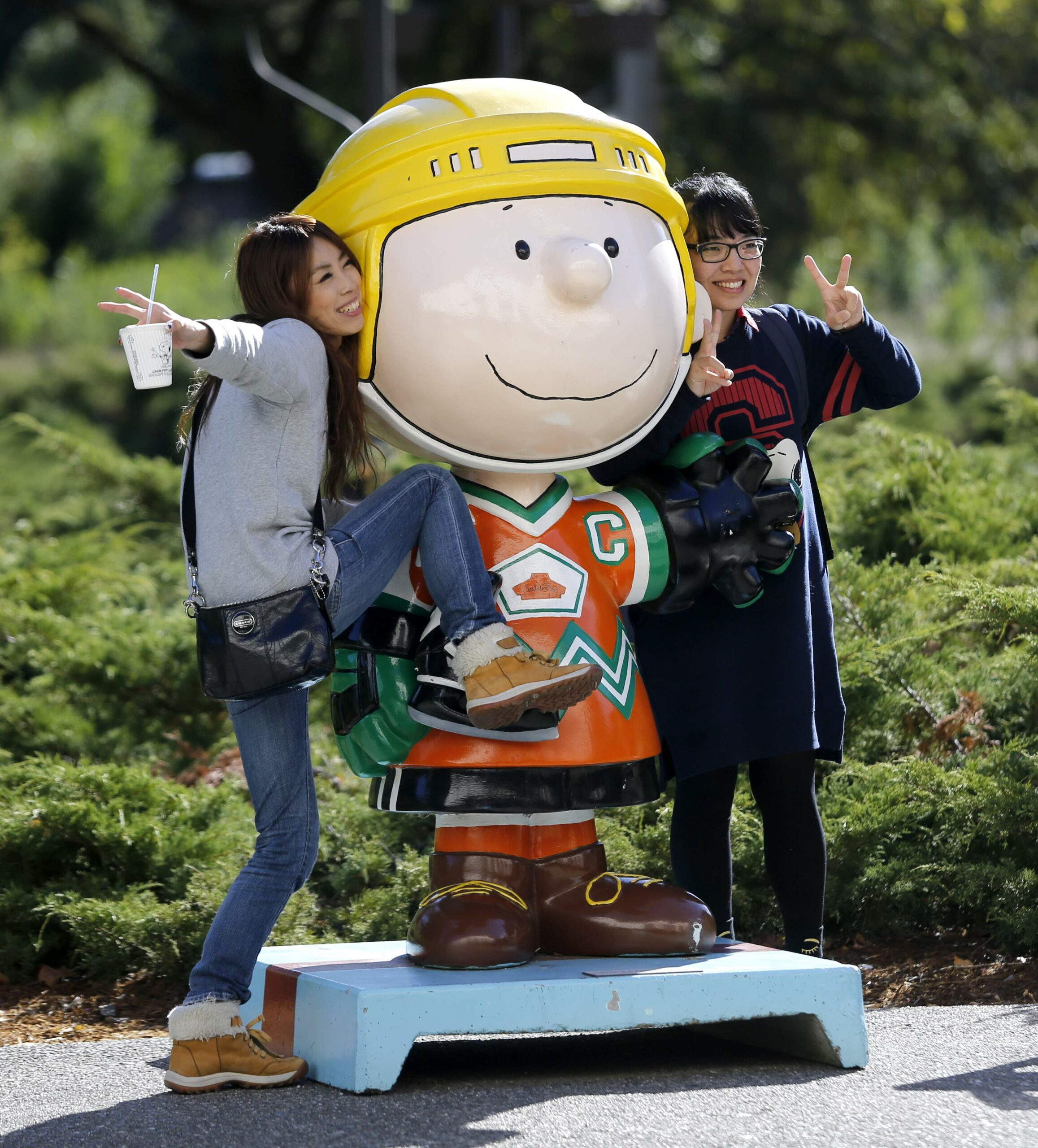 Sakiko Yazawa, left, and Chisa Tatsumi, tourists from Japan, pose as their friend, Yuka Shimada, takes their photo with Charlie Brown at the Redwood Empire Ice Arena in Santa Rosa, on Wednesday, November 4, 2015. (BETH SCHLANKER/ The Press Democrat)