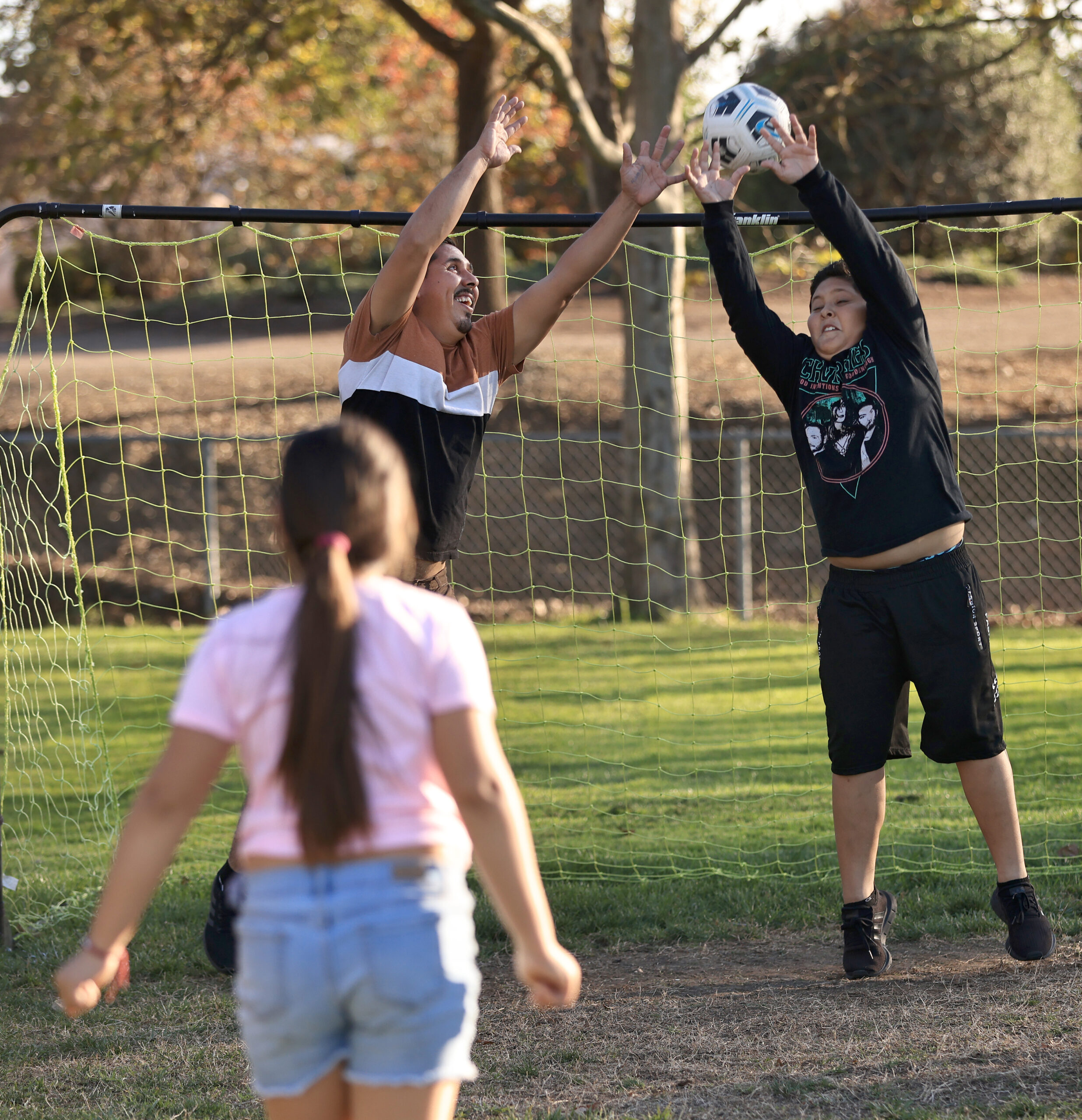 Adrian, 13, and his father Julio Pena play soccer with sister and daughter Angelique, 10, Wednesday, Nov. 16, 2022 in Healdsburg. The family was granted asylum, and drove through the border legally on Oct. 19 from Tepalcatepec, Michoacan in Mexico. . (Kent Porter / The Press Democrat) 2022