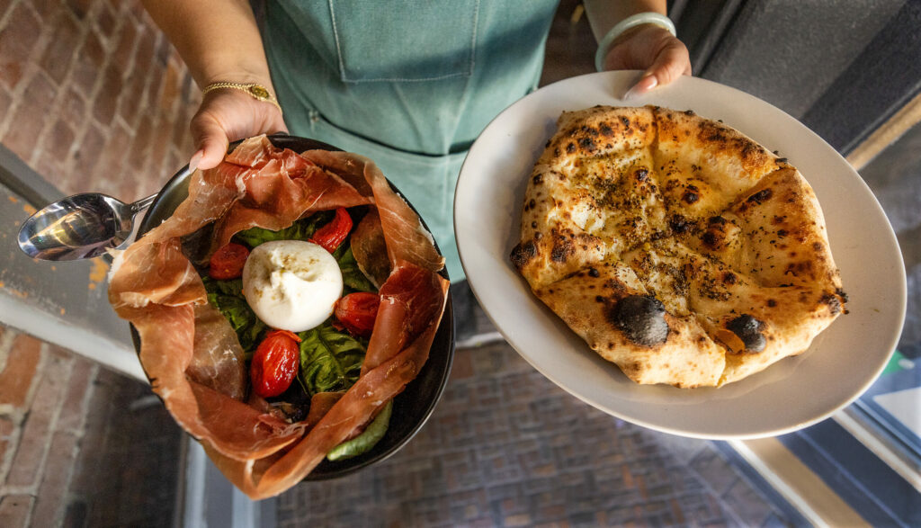 Burrata Caprese aged baby tomato confit served with creamy burrata cheese basil, EVOO surrounded by proscuitto, left, and Focaccia All' Aglio, Napoletan garlic bread with oregano and lots of EVOO from L'Oro di Napoli in downtown Santa Rosa March 24, 2023. (John Burgess/The Press Democrat)