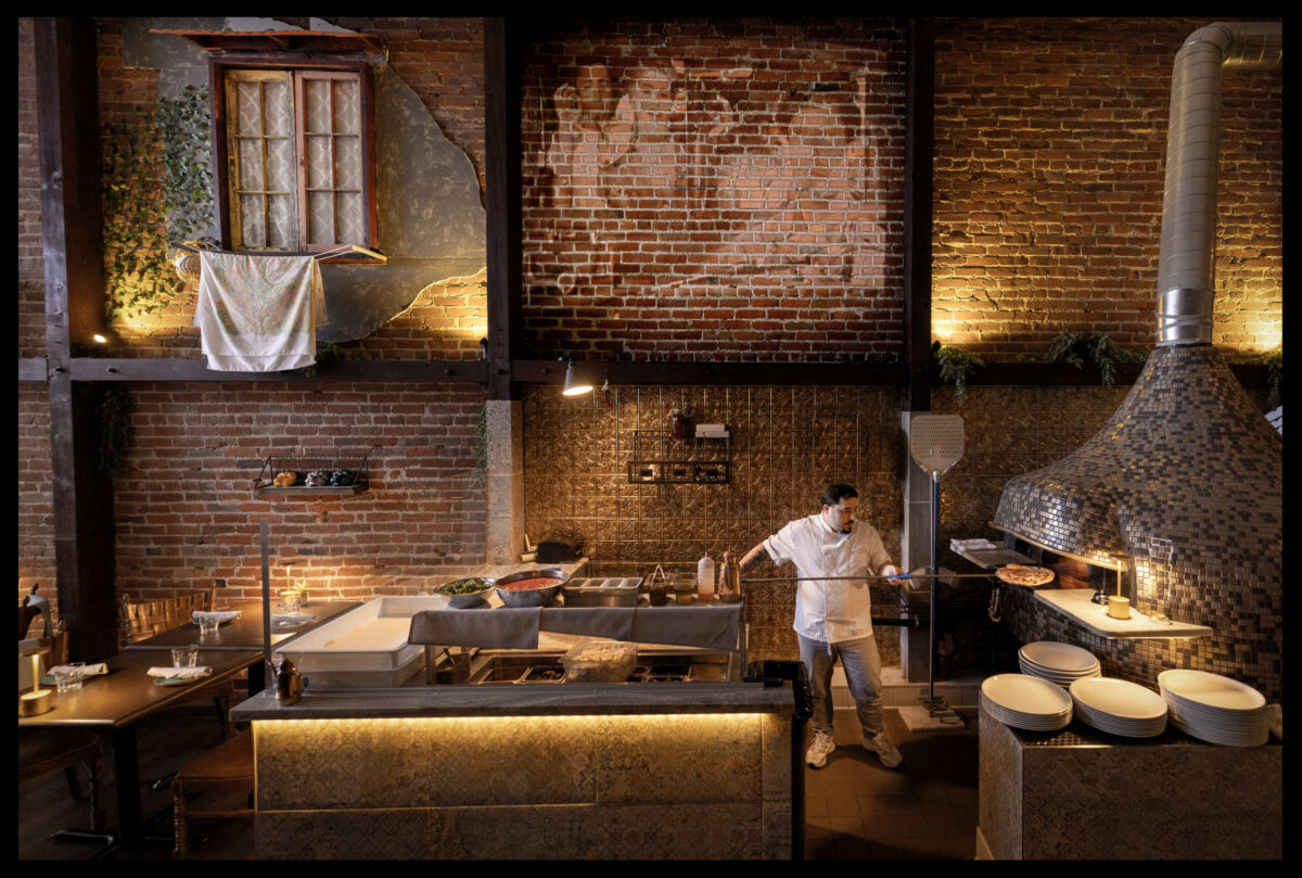 Loro di Napoli owner Domenico De Angelis works his magic at the pizza oven in downtown Santa Rosa March 24, 2023. De Angelis designed the space that projects old Italian black-and-white films on the brick above the pizza oven. (John Burgess/The Press Democrat)