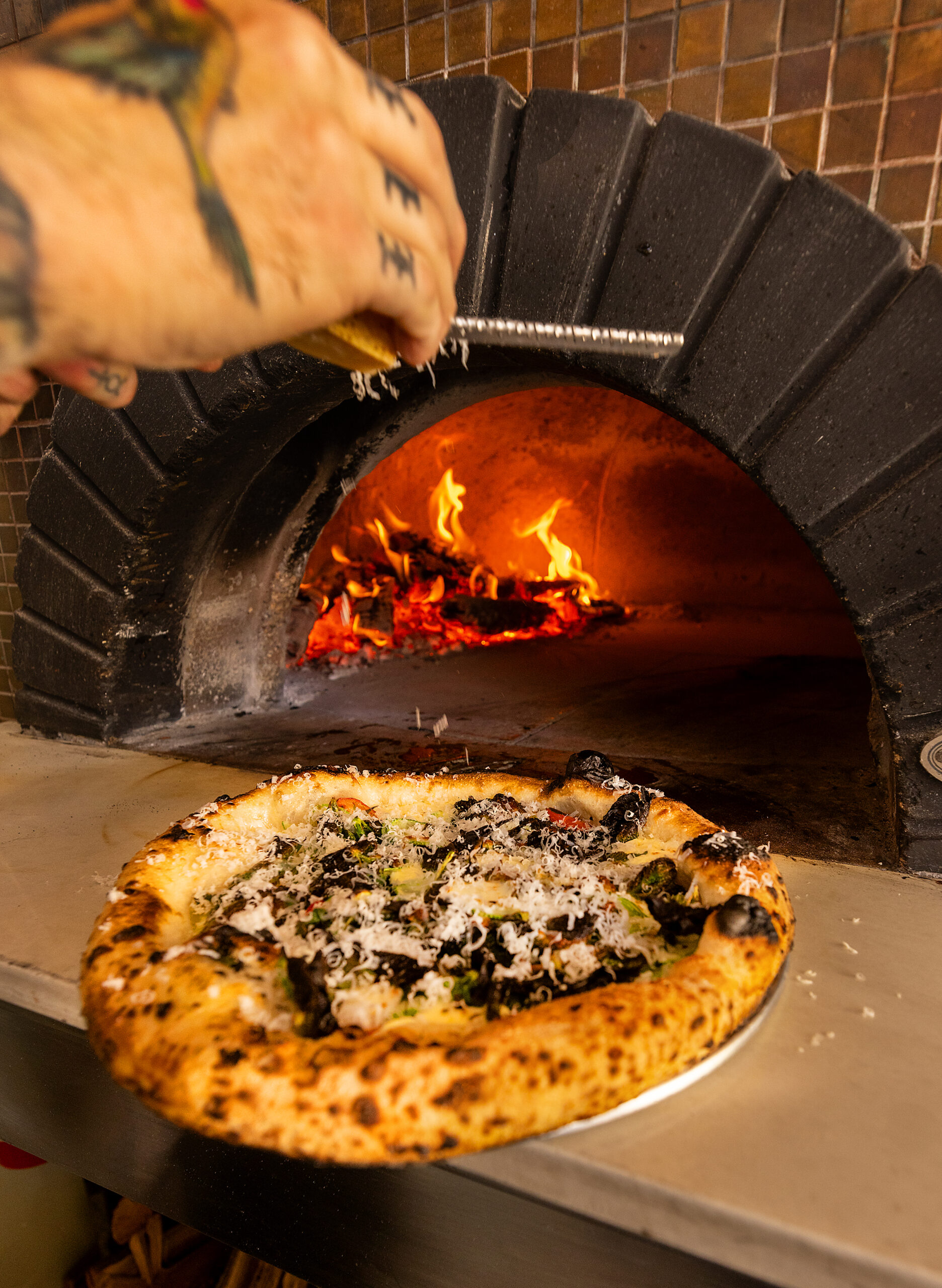 Topping a Margherita pizza with parmesan from Molti Amici in Healdsburg Wednesday, July 19, 2023. (John Burgess/The Press Democrat)