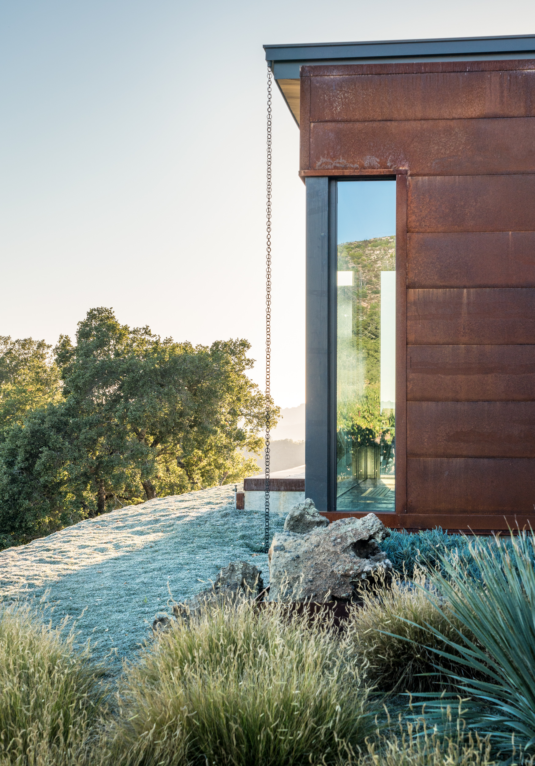A simplified palette of Corten steel, iron, wood, and concrete complement the structural rammed earth walls and keep the focus on the surrounding landscape and vineyards. (Adam Potts)