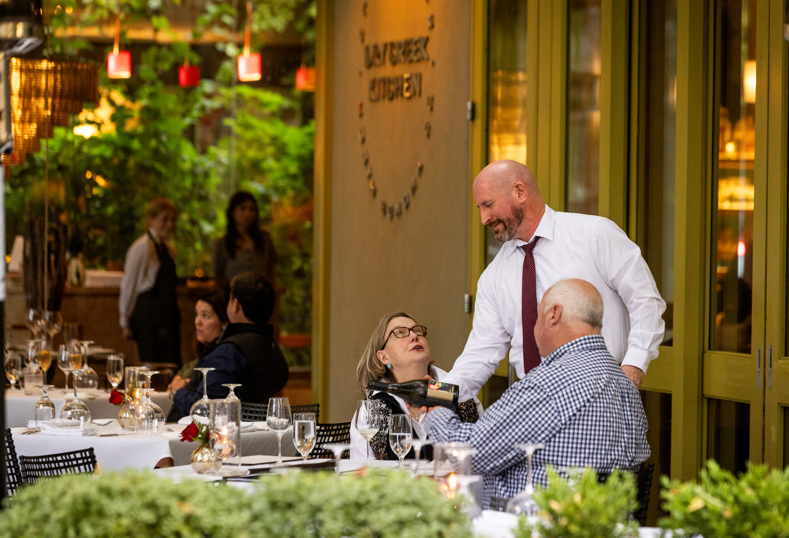 Server Adam Krom pours wine for customers on the patio at Dry Creek Kitchen on the square in Healdsburg Thursday, November 2, 2023. (John Burgess/The Press Democrat)
