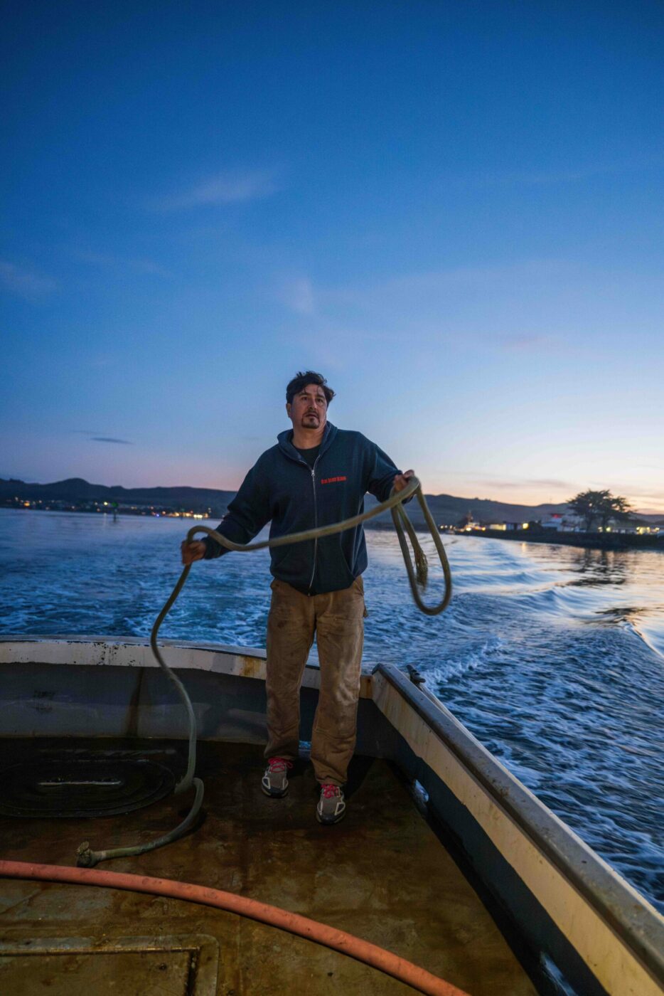 Jackson hauls lines while exiting the harbor in Bodega Bay. Early in the season, the rough ropes cause hands to swell and blister. (James Joiner)