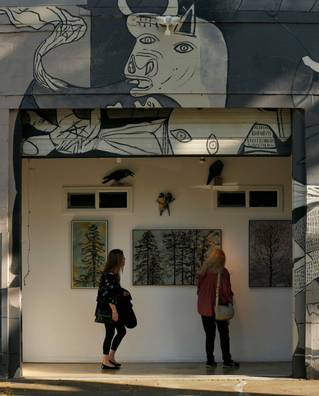 Kim Romero, left, of Healdsburg and Anet Dunne of Santa Rosa view paintings by artist Corrine Haverinen that are displayed at the front of Backstreet Gallery and Studios in the SOFA arts district of Santa Rosa, California, on Friday, May 3, 2019. (Alvin Jornada / The Press Democrat)