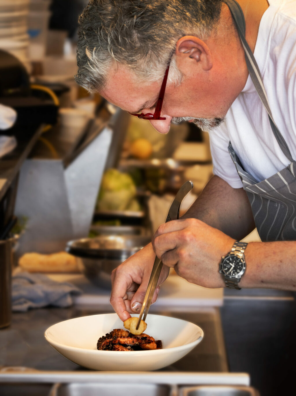 Tisza Bistro chef/owner Krisztian Karkus plates a Charred Octopus starter Monday, February 12, 2024 in Healdsburg. (Photo by John Burgess/The Press Democrat)