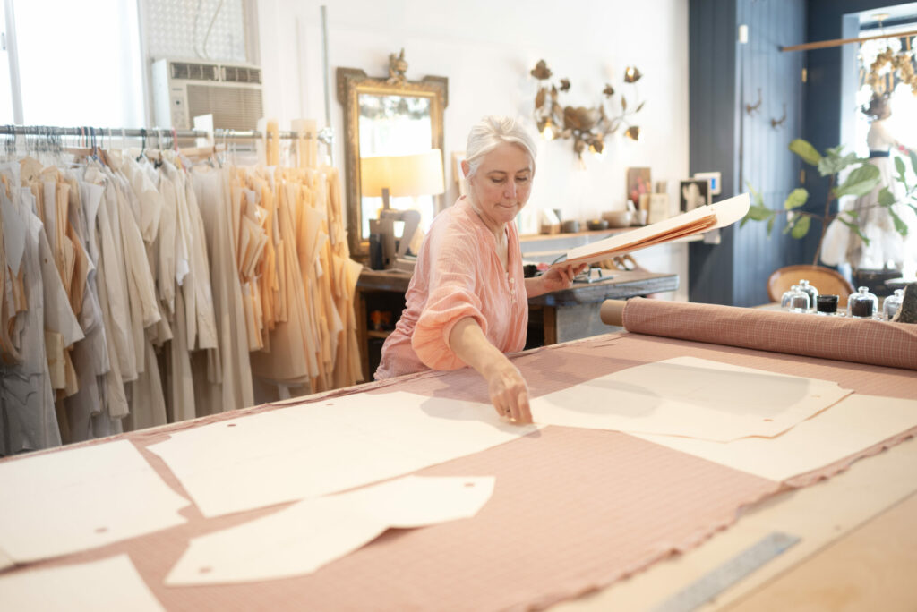 Designer Theresa Hughes arranges pieces of a pattern onto a bolt of imported fabric in her Santa Rosa workshop. (Erik Castro/for Sonoma Magazine)