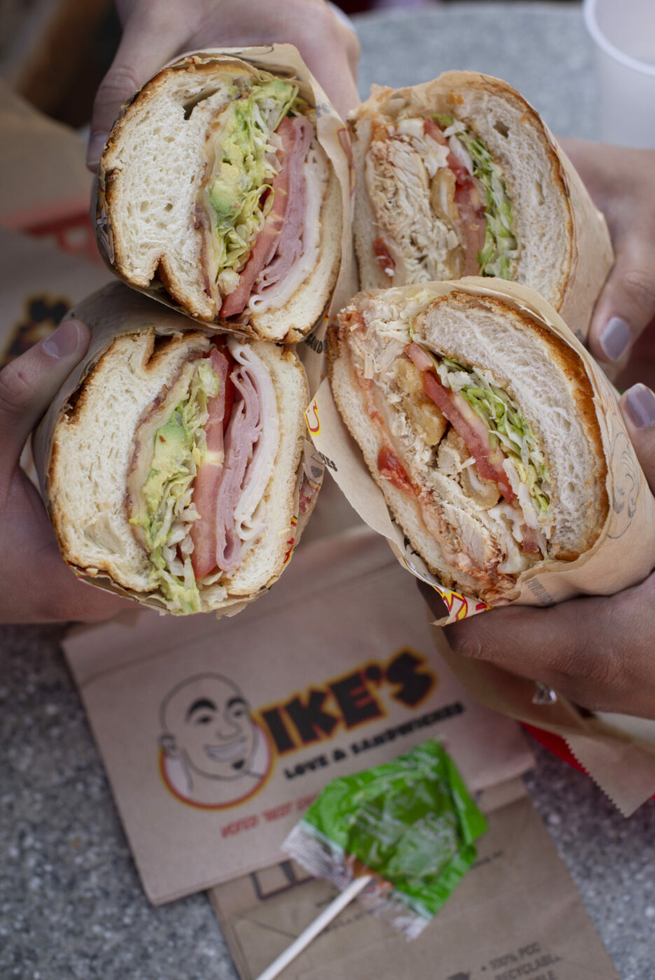 A couple prepares to eat the Lincecum sandwich, left, made with avocado, bacon, ham, havarti and turkey and the Rum Rum sandwich made with halal chicken, marinara and provolone cheese at Ike's Place in Santa Rosa, California. September 6, 2018 (Photo: Erik Castro/for The Press Democrat)