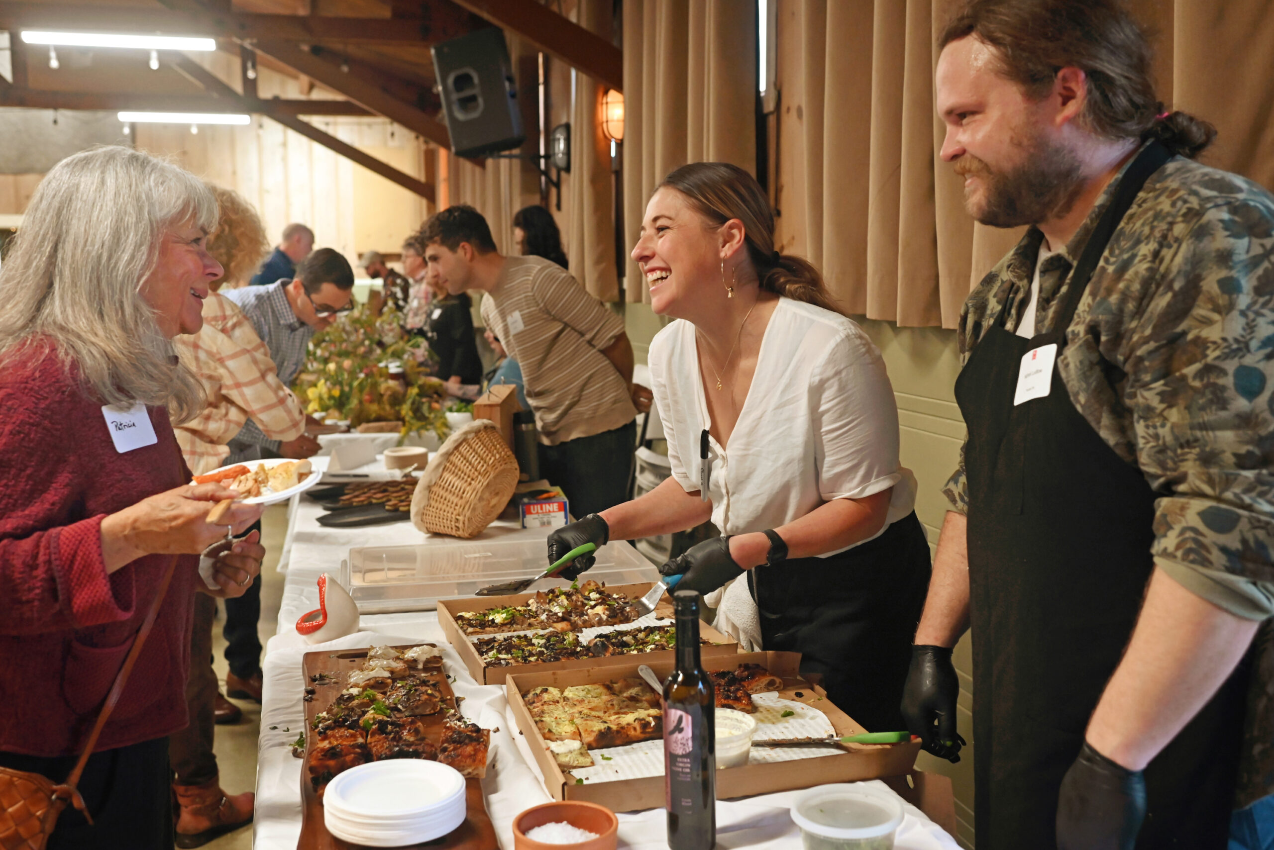 Leith Leiser-Miller and Nicholi Ludlow, right, serving up their Psychic Pie pizza to attendees during the Snail of Approval awards ceremony held at Grange Hall in Sebastopol, Wednesday, Feb. 28, 2024. (Erik Castro / For The Press Democrat)