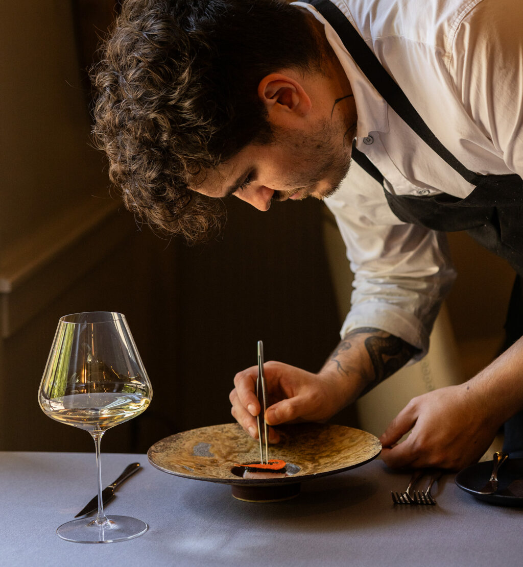 Chef Craig Wilmer places a shrimp cracker, created with a 3D printed stencil, on top of his Prawn Tartar wrapped in heart of palm with a tomatoes oil and drops of dill oil at the Farmhouse restaurant on River Road in Forestville, Friday, Aug. 18, 2023. (John Burgess / The Press Democrat)