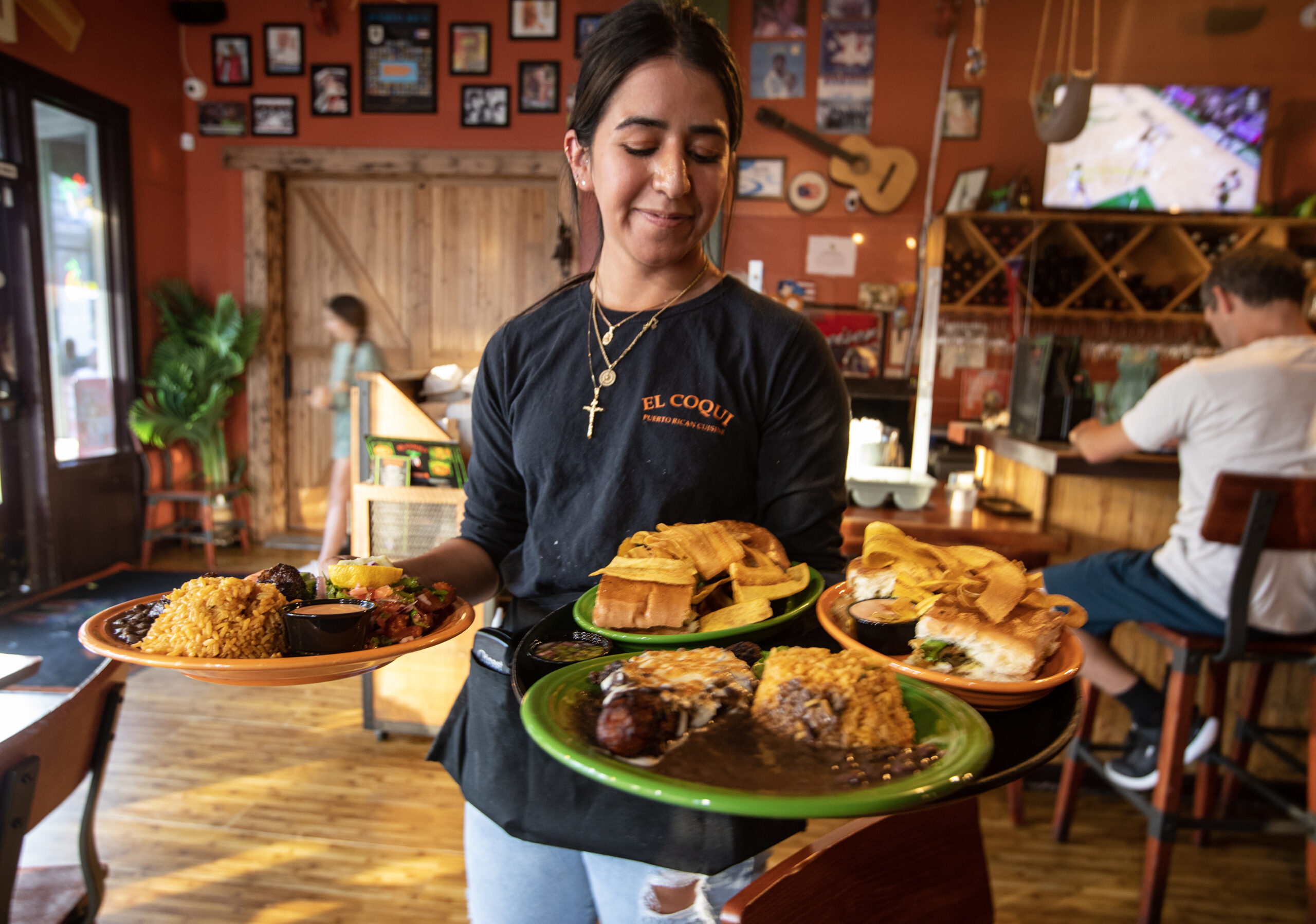 An employee of El Coqui restaurant takes plates to guests in Santa Rosa
