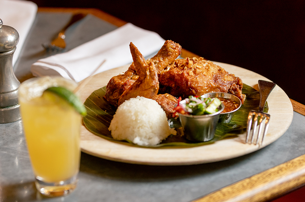 Hat Yai Fried Chicken with sticky rice, cucumber salad and sweet + sour sauce with a Mucho Micho cocktail from Underwood Bar and Bistro Friday March 21, 2025, in Graton. (John Burgess / The Press Democrat)