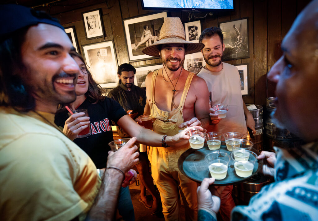 Auctioneer Nick Schwanz, center in hat, and his friends grab Champagne to celebrate raising more than million for local charities over the past 20 years on Give Back Tuesdays, June 24, 2025, at the Rainbow Cattle Co. in Guerneville. (John Burgess / Press Democrat)