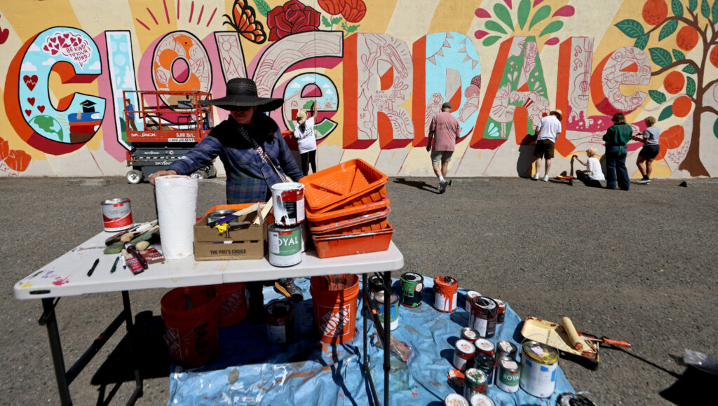 Artist Blanca Molina prepares to complete a mural in downtown Cloverdale, Wednesday Aug. 21, 2024, that highlights the community's Latino culture. From left, background are Marta Cruz, Tim McDonald, Bob Scott, Sara Hagen and Laura Arreguin. (Kent Porter / The Press Democrat)