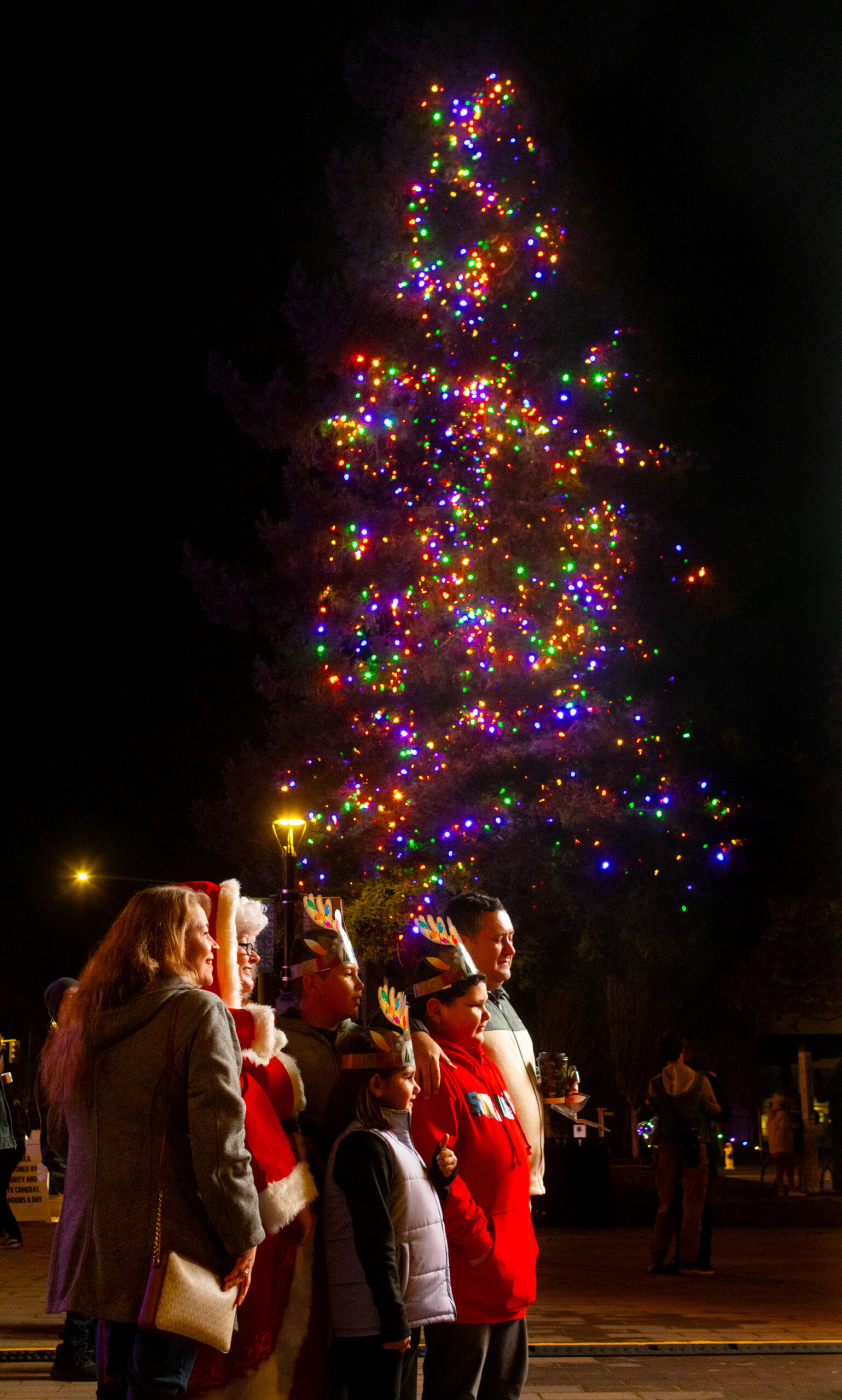 People pose in front of the newly lighted Christmas Tree at the conclusion of Sonoma County’s Winter Lights and 41st Annual Tree Lighting Celebration, at the Old Courthouse Square in Santa Rosa, Friday, November 29, 2024. (Darryl Bush / For The Press Democrat)