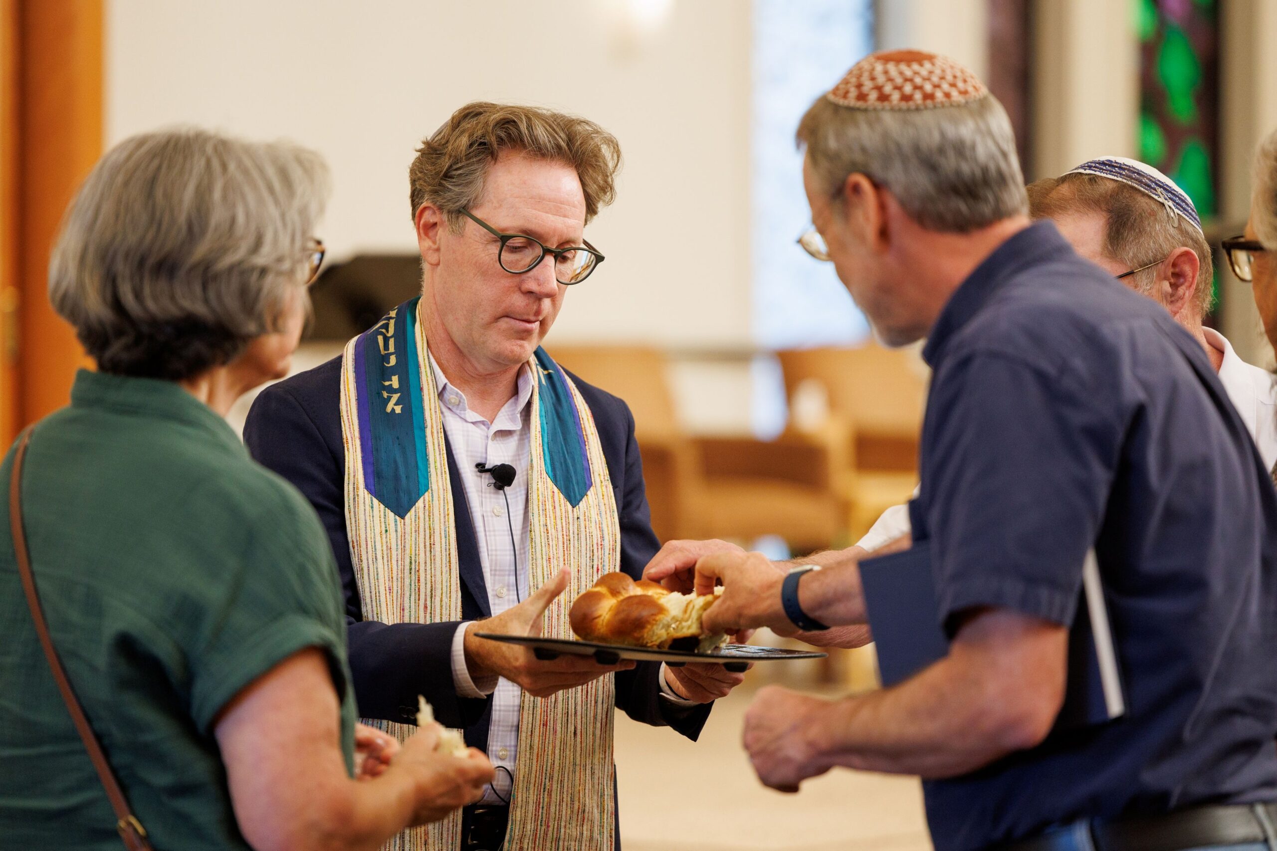 Rabbi Jeremy Morrison distributes a loaf of challah to his congregation during Shabbat at Congregation Shomrei Torah on August 15, 2025. (Abraham Fuentes/For The Press Democrat)
